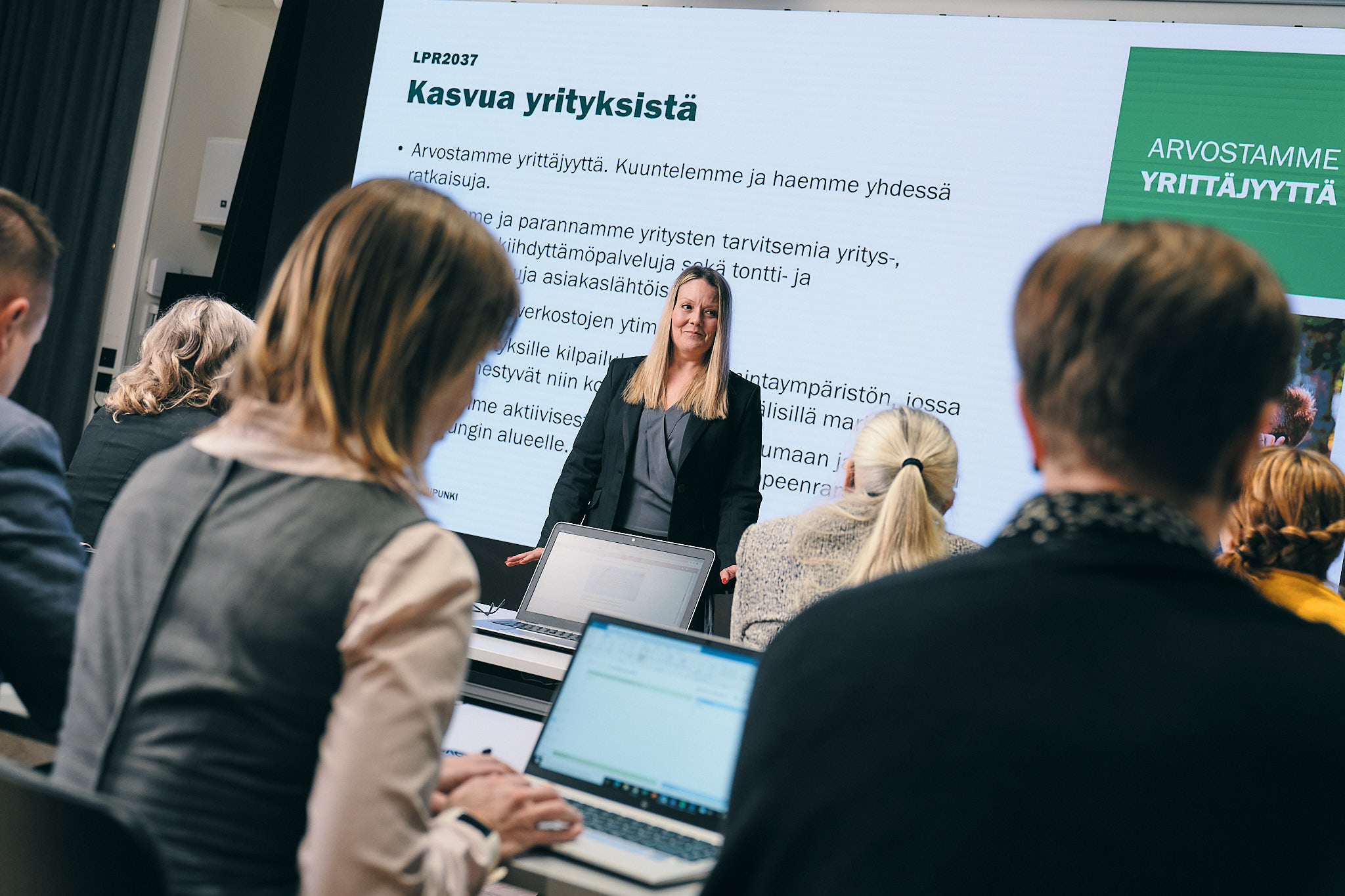 Ihmiset seuraavat vaalea hiuksisen naisen esitystä, joka on otsikoitu ”Lpr strategia kasvua yrityksistä”